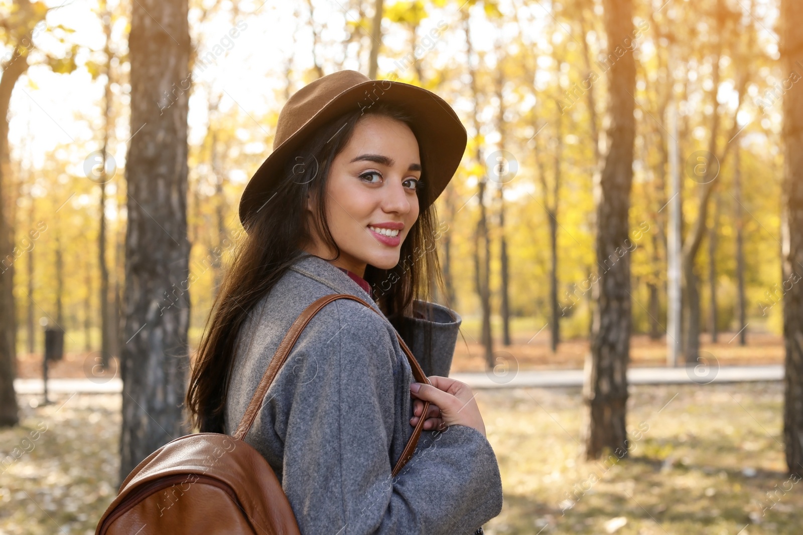 Photo of Young beautiful woman with backpack in park. Autumn walk