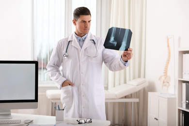Photo of Professional orthopedist examining X-ray picture in clinic