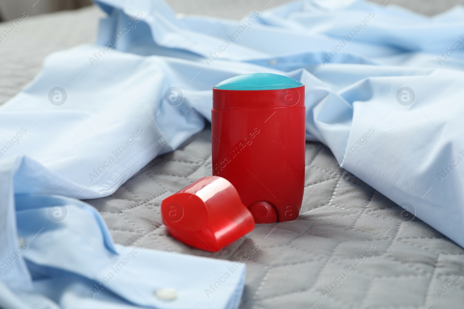 Photo of Male stick deodorant and light blue shirt on grey plaid, closeup