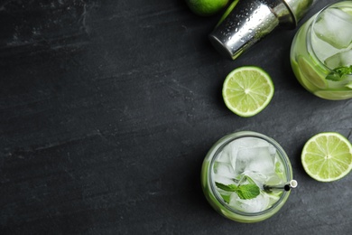 Photo of Delicious mojito and ingredients on black table, flat lay. Space for text
