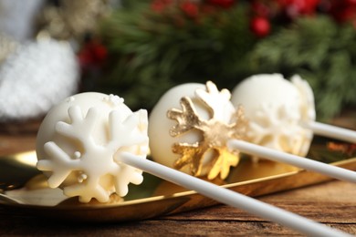 Photo of Delicious Christmas themed cake pops on golden plate, closeup