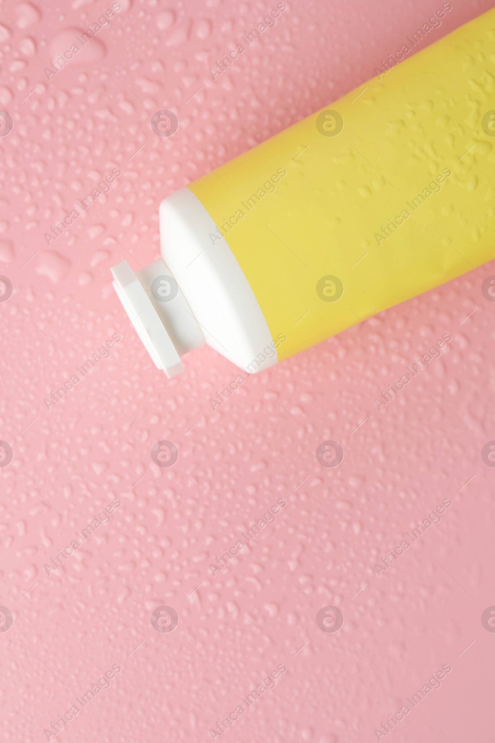 Photo of Moisturizing cream in tube on pink background with water drops, top view. Space for text