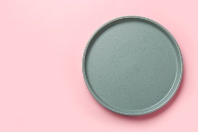 Photo of Empty grey ceramic plate on pink background, top view. Space for text