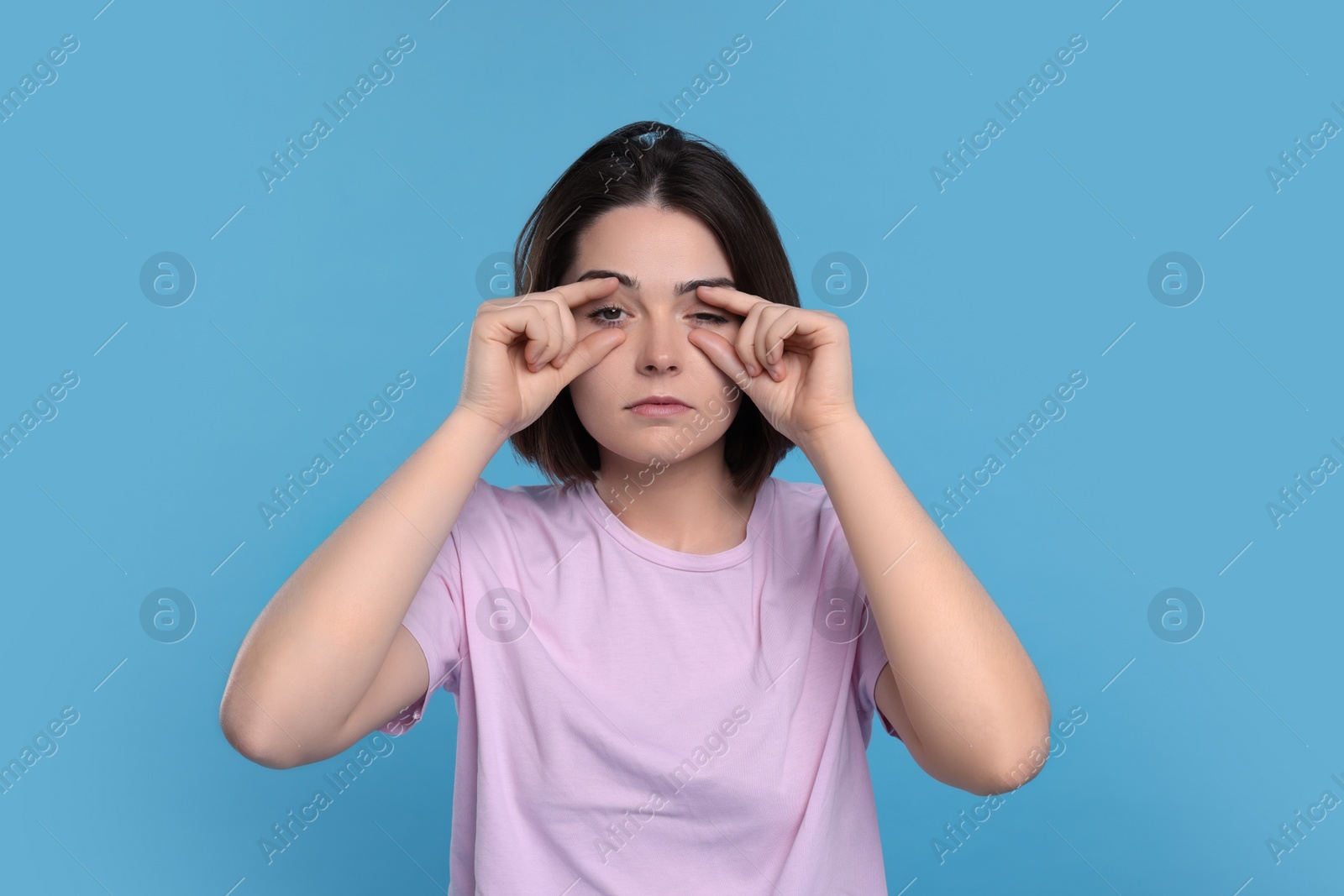 Photo of Sleepy young woman on light blue background. Insomnia problem