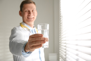 Photo of Nutritionist with glass of water near window in office. Space for text