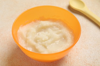 Baby food. Bowl with cauliflower puree served on beige textured table, closeup