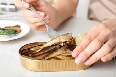 Photo of Woman with tin can of conserved fish at table