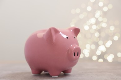Photo of Piggy bank on grey table against blurred lights