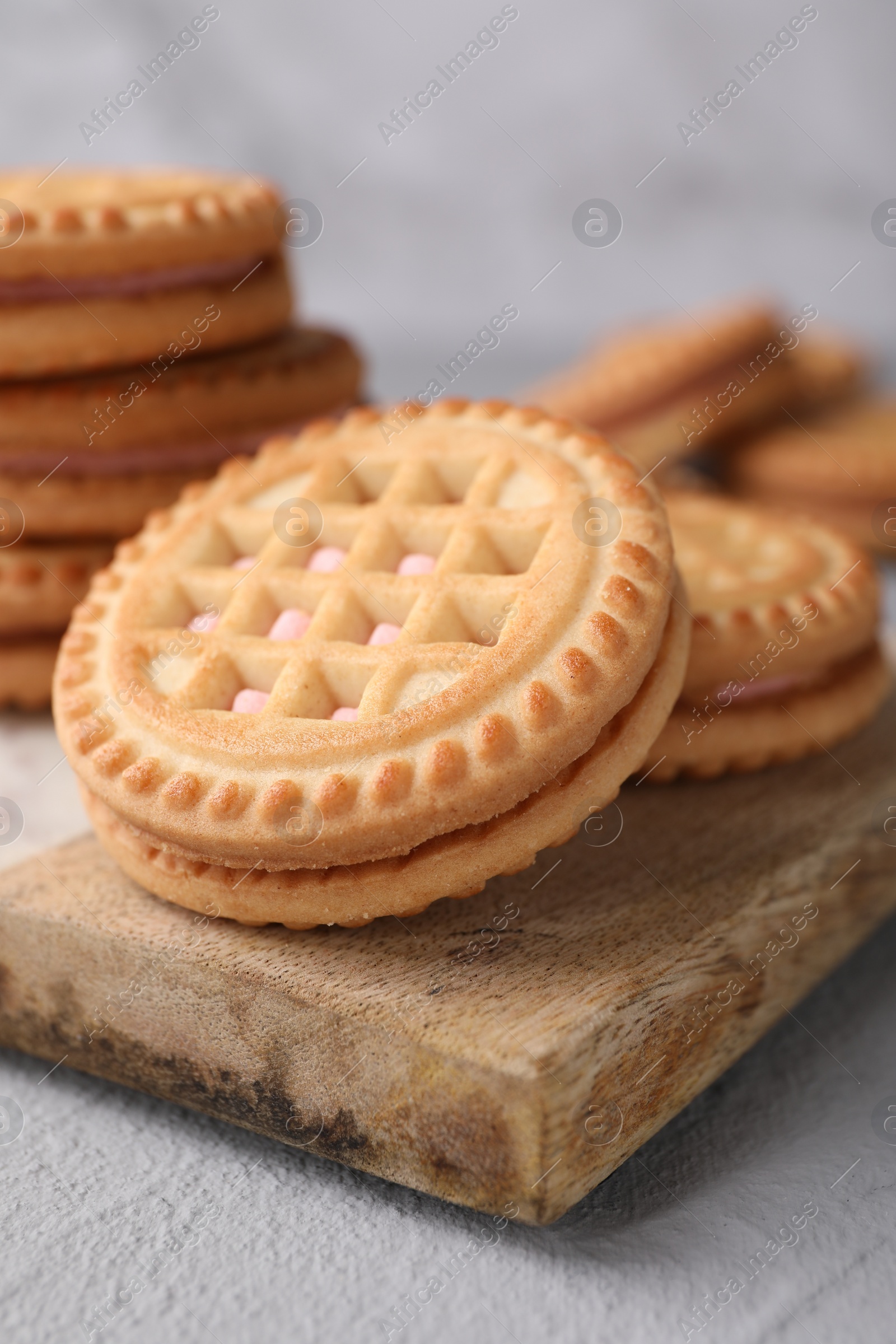 Photo of Tasty sandwich cookies with cream on light grey table, closeup