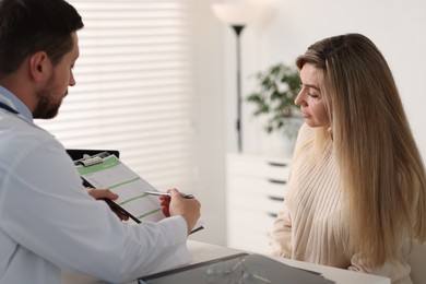 Professional doctor working with patient at white table in hospital