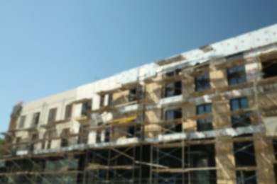 Blurred view of unfinished building with scaffolding against blue sky