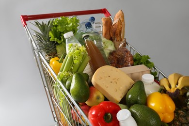 Shopping cart full of groceries on grey background, closeup