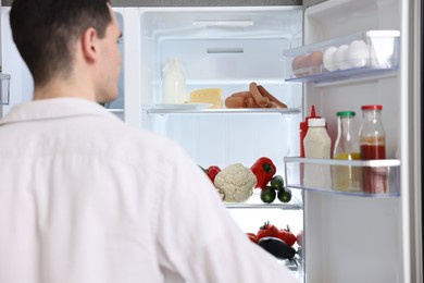 Man near refrigerator in kitchen at home, back view