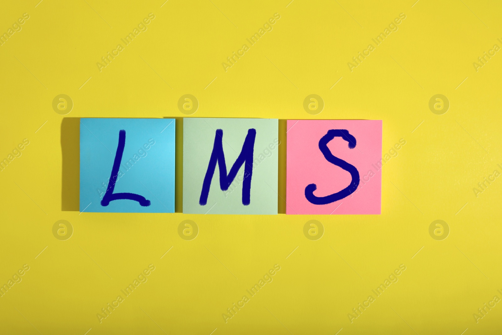 Image of Learning management system. Colorful sticky notes with abbreviation LMS on yellow background, top view