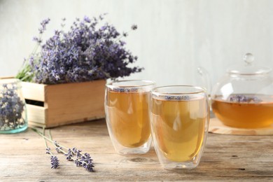 Photo of Fresh delicious tea with lavender in glass on wooden table