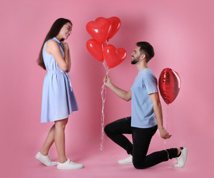 Photo of Lovely couple with heart shaped balloons on pink background. Valentine's day celebration