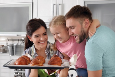 Beautiful woman treating her family with freshly oven baked buns in kitchen