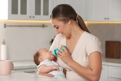 Photo of Mother feeding her cute child with infant formula indoors