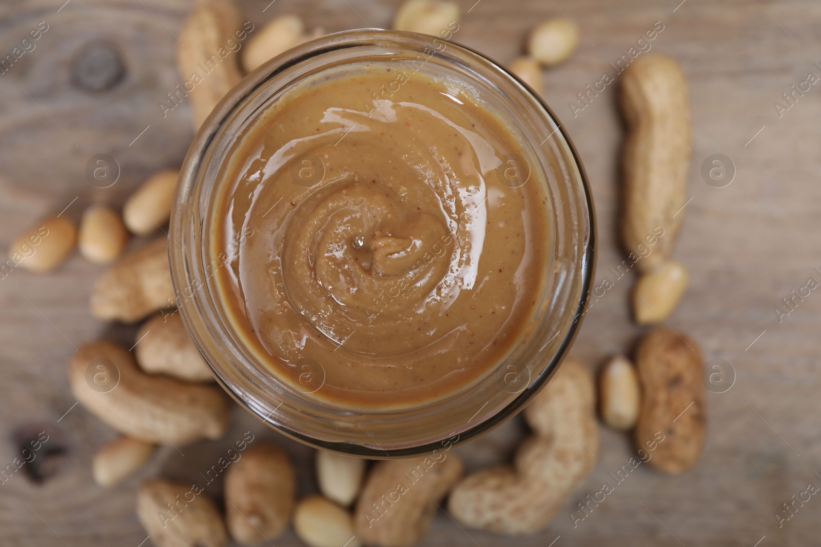 Photo of Tasty peanut nut paste in jar on table, top view