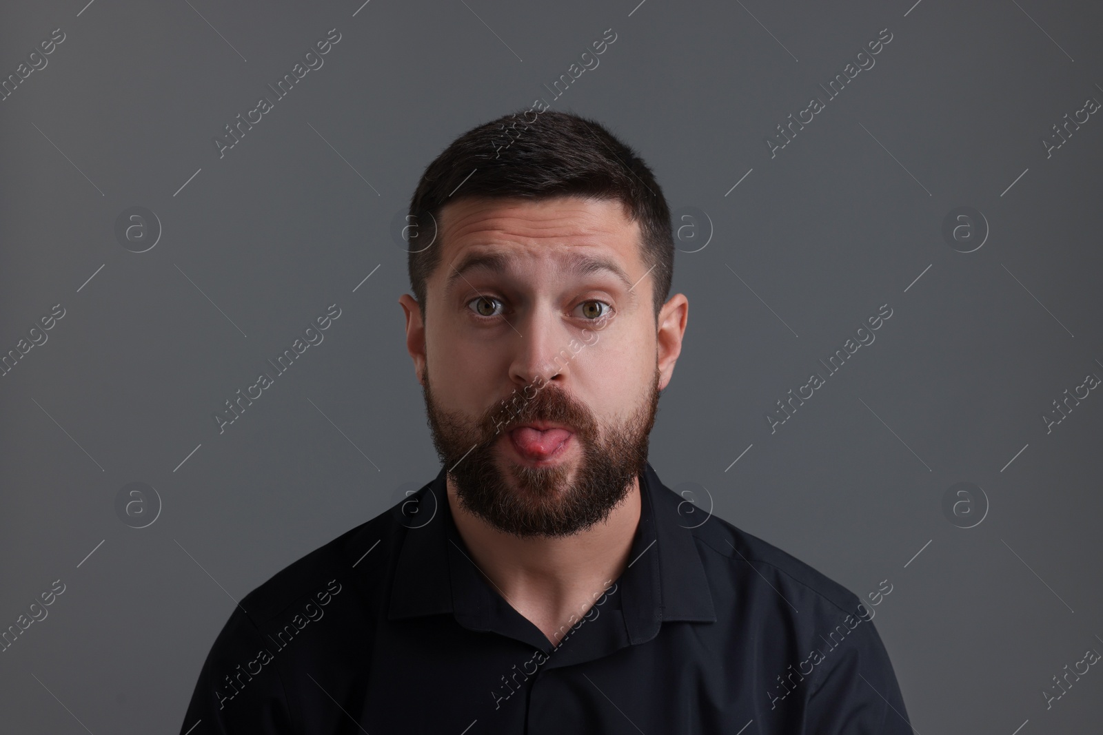Photo of Personality concept. Handsome man showing tongue on grey background