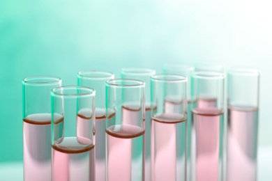 Photo of Many test tubes with liquid on color background, closeup