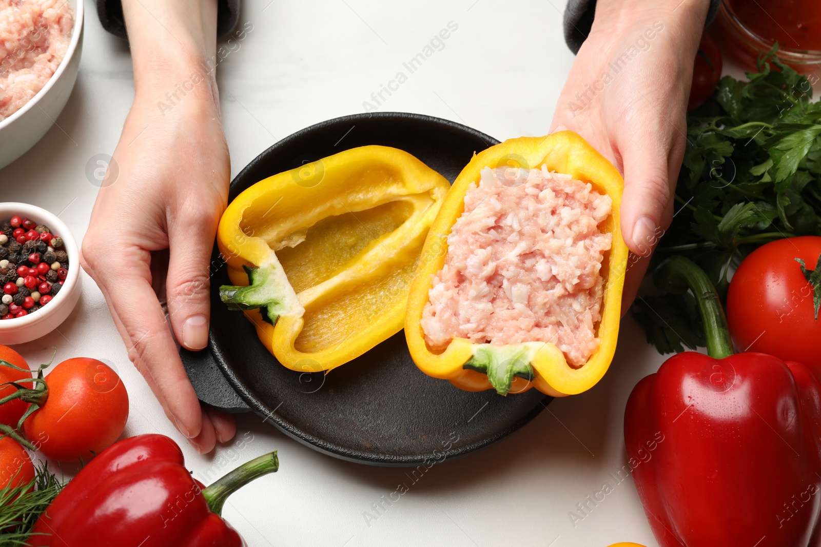 Photo of Woman making stuffed peppers with ground meat at white table, closeup