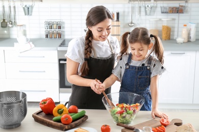 Photo of Young nanny with cute little girl cooking together in kitchen