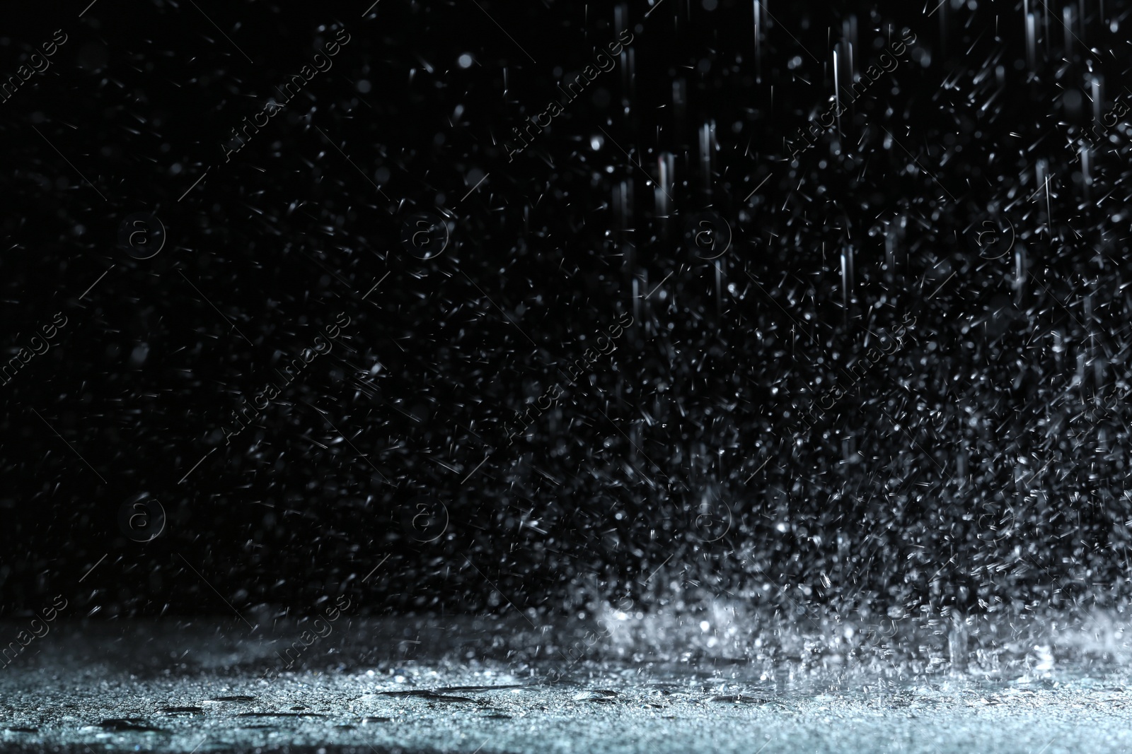 Photo of Heavy rain falling down on ground against dark background