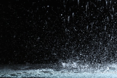 Photo of Heavy rain falling down on ground against dark background