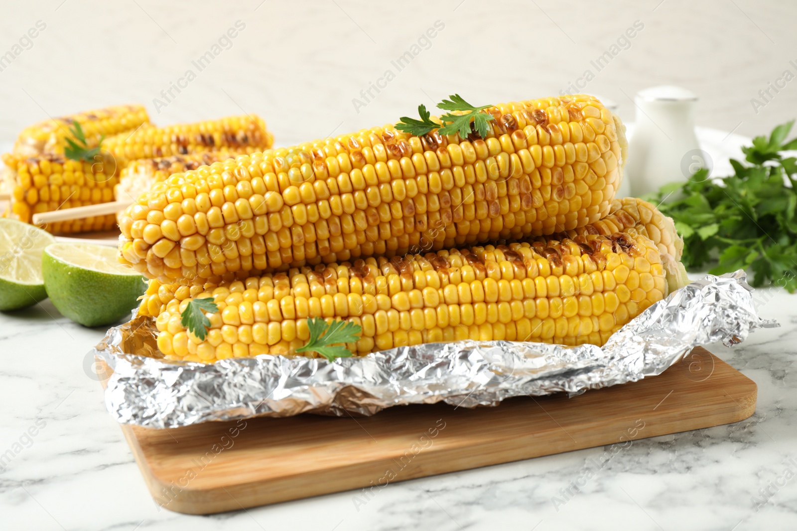 Photo of Tasty grilled corn on white marble table