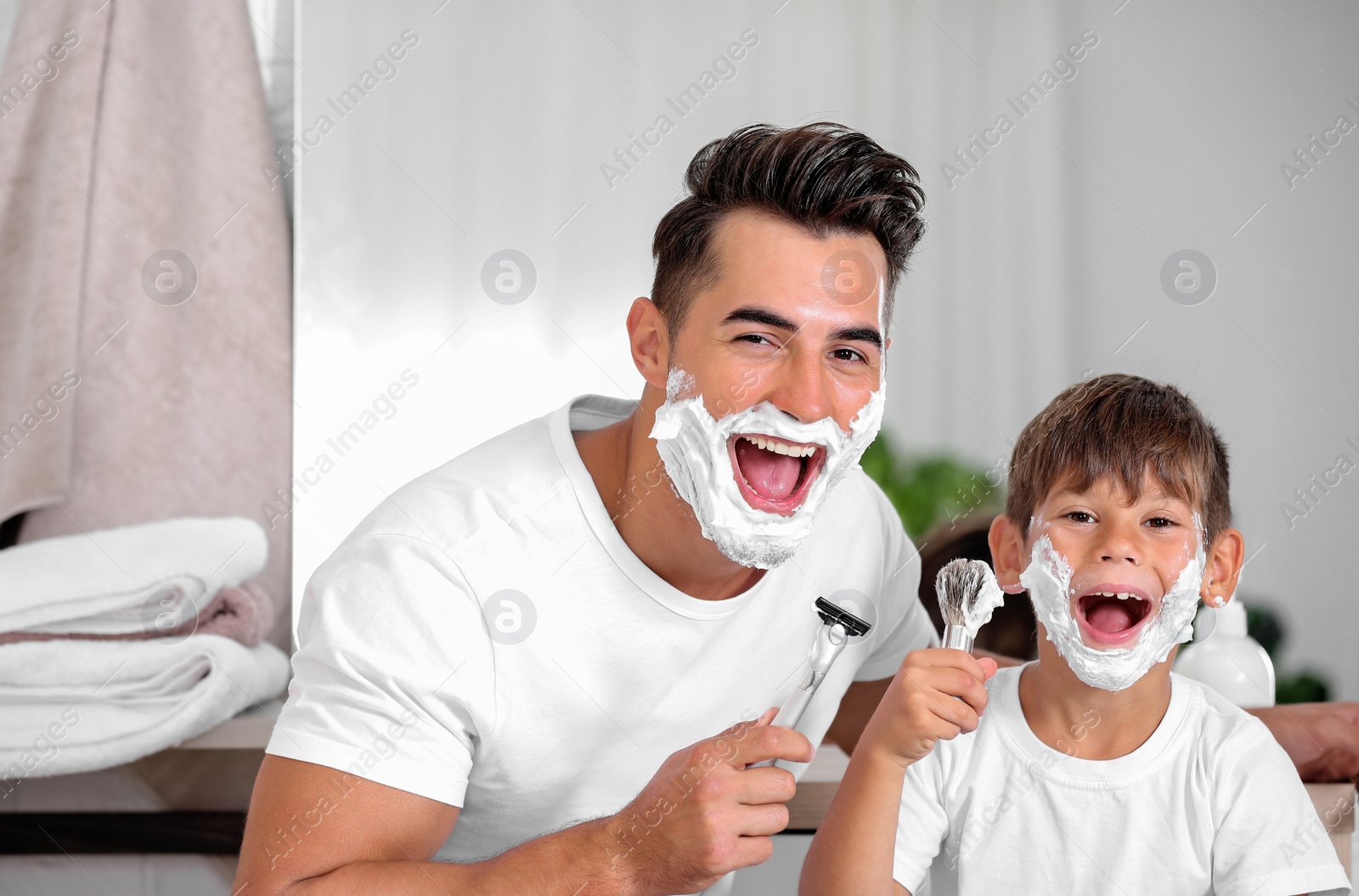 Photo of Father and son having fun while shaving in bathroom