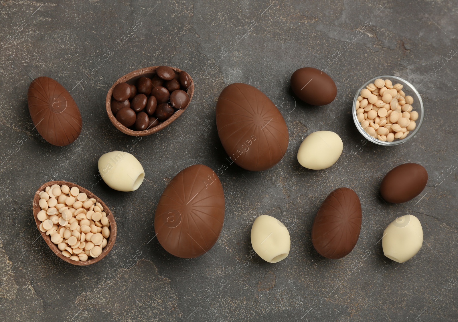 Photo of Sweet chocolate eggs and candies on grey table, flat lay