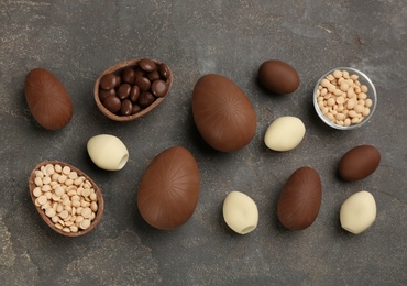 Sweet chocolate eggs and candies on grey table, flat lay