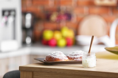 Jar with coconut oil and tasty pastry on table in kitchen. Healthy cooking