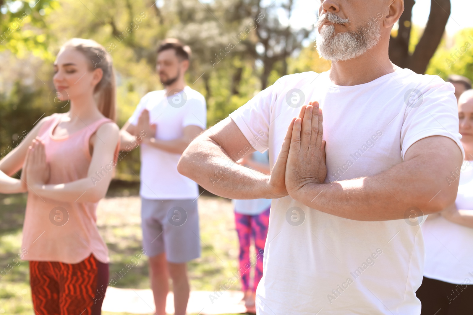 Photo of Group of people practicing yoga in park on sunny day