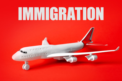 Toy plane and word IMMIGRATION on red background