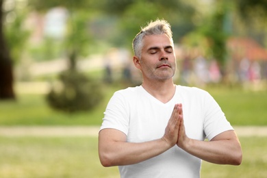 Man practicing yoga in park at morning, space for text