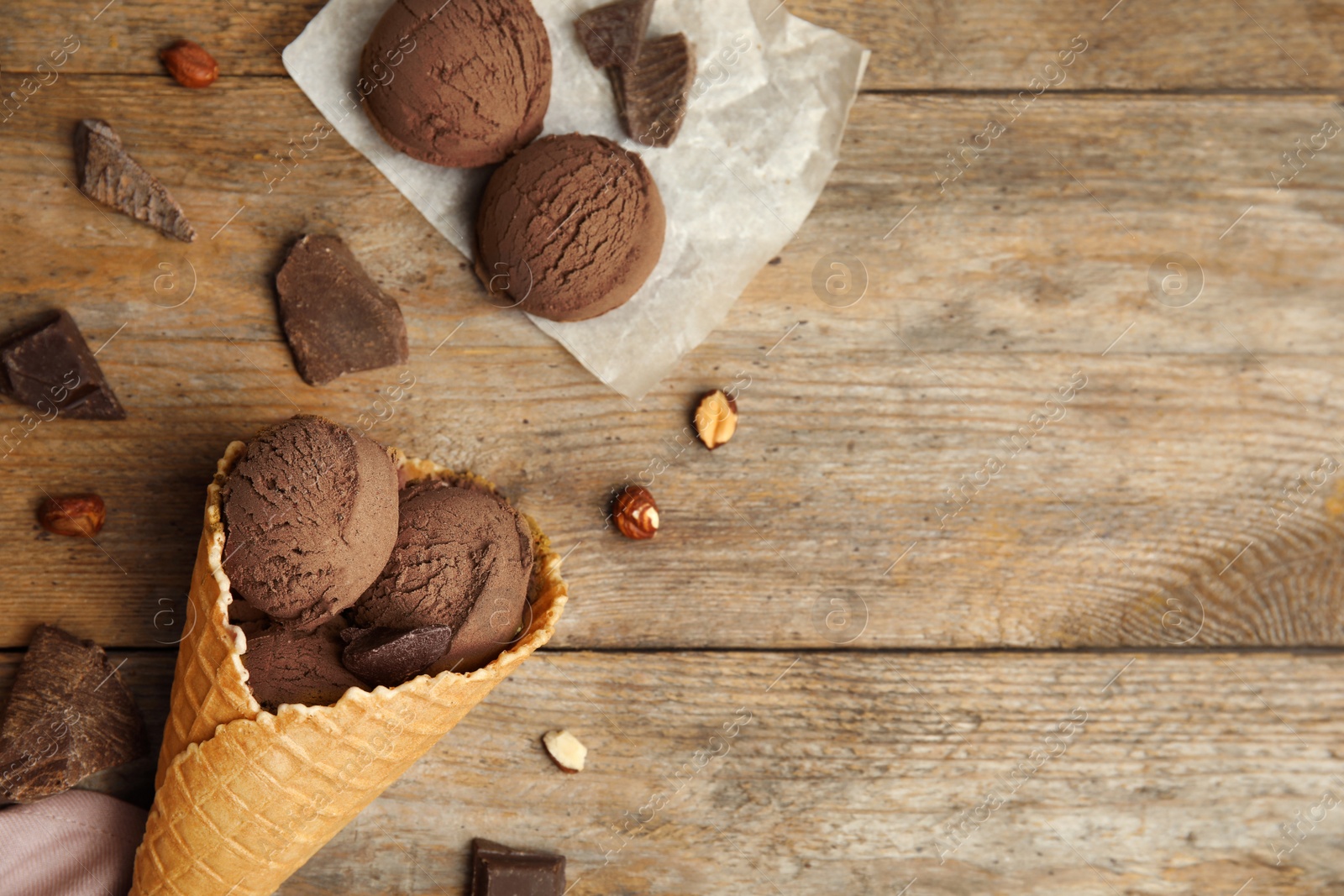 Photo of Flat lay composition with delicious ice cream in waffle cone on wooden table, space for text