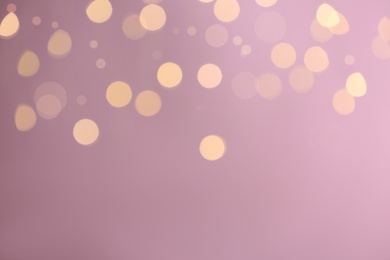 Blurred view of festive lights on purple background, space for text. Bokeh effect