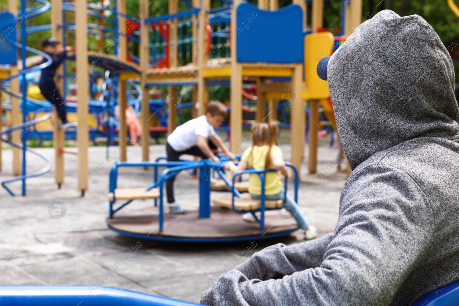 Photo of Suspicious adult man spying on kids at playground, space for text. Child in danger