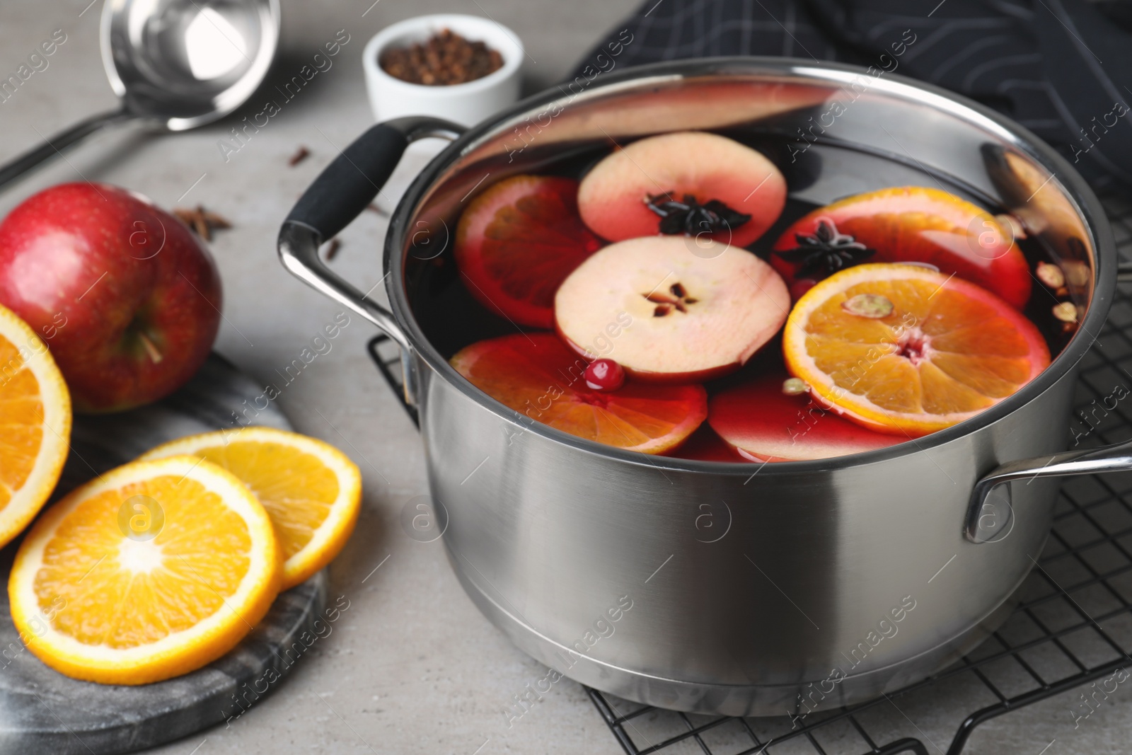 Photo of Delicious mulled wine and ingredients on grey table, closeup