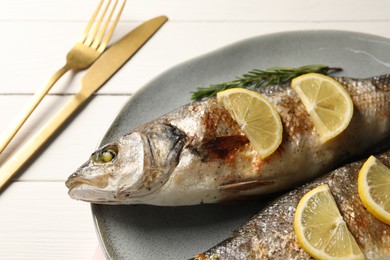 Photo of Delicious baked fish served on white wooden table, closeup