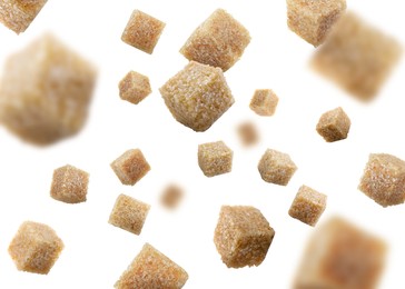 Brown cane sugar cubes falling on white background