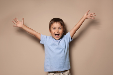 Portrait of happy little boy on beige background