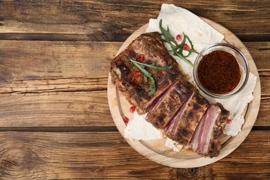 Photo of Delicious grilled ribs served on wooden table, top view