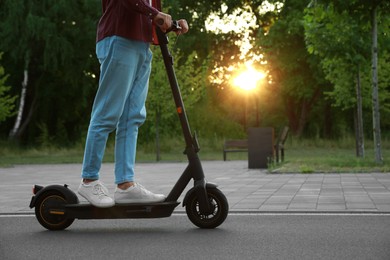 Photo of Man riding modern electric kick scooter in park, closeup. Space for text