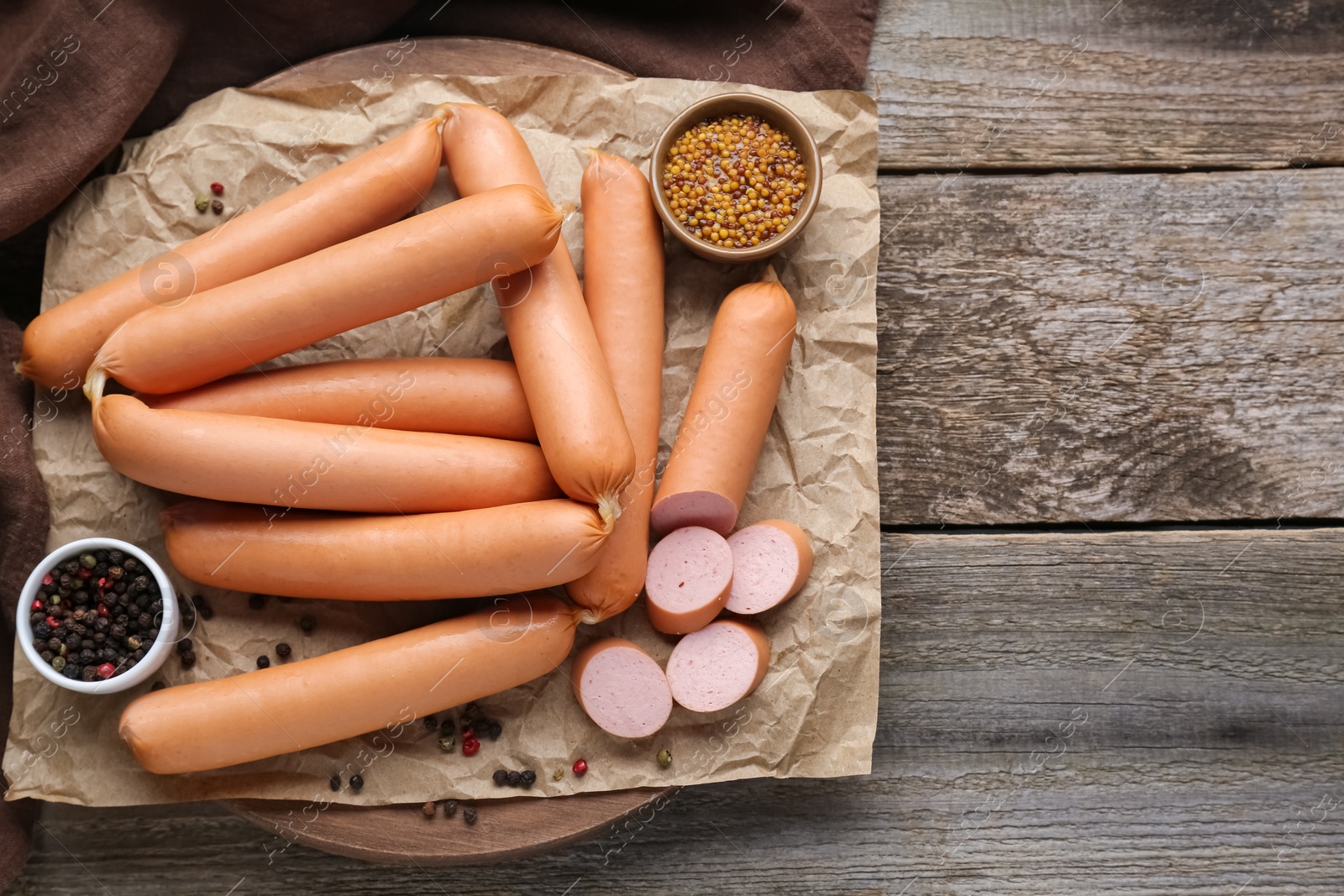 Photo of Tasty sausages, peppercorns and mustard on wooden table, flat lay with space for text. Meat product