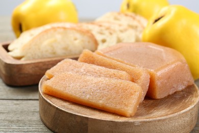 Tasty sweet quince paste, fresh fruits and bread on wooden table, closeup
