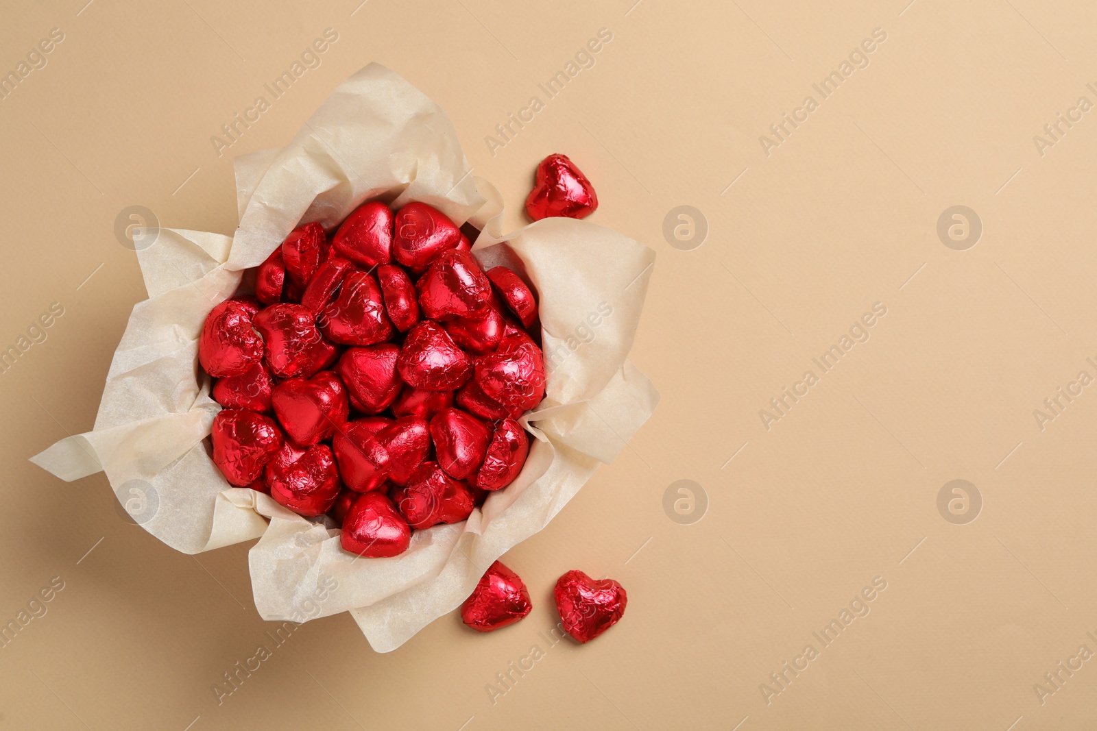 Photo of Beautiful heart shaped chocolate candies on beige background, flat lay with space for text