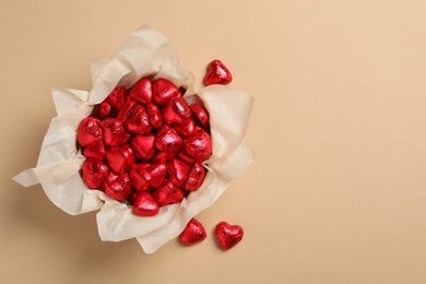 Beautiful heart shaped chocolate candies on beige background, flat lay with space for text